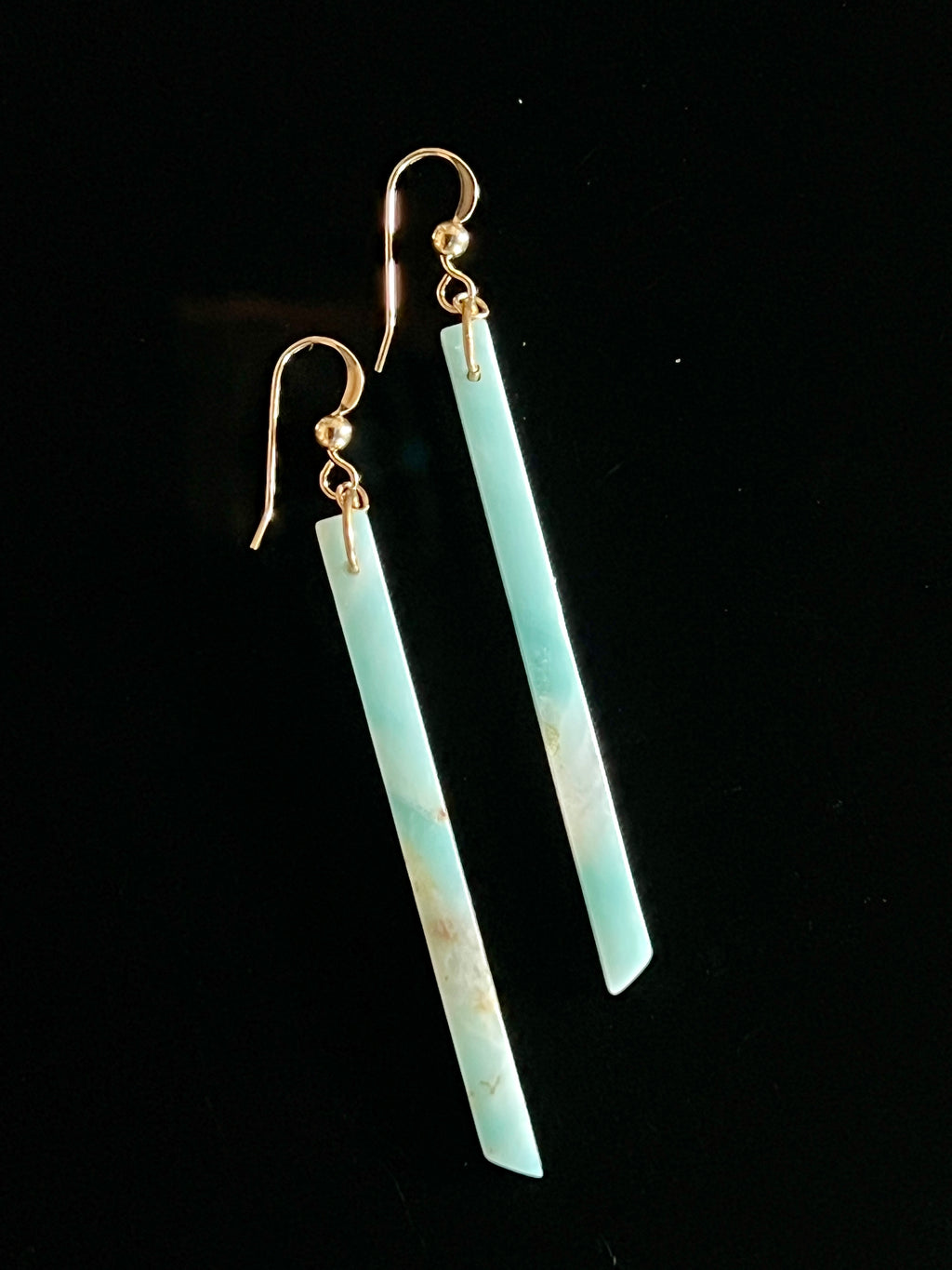 Pair of Amazonite long bar drop earrings with 14K gold fill fish hook wires on a black background, showing vivid blue-green stone with natural cream inclusions