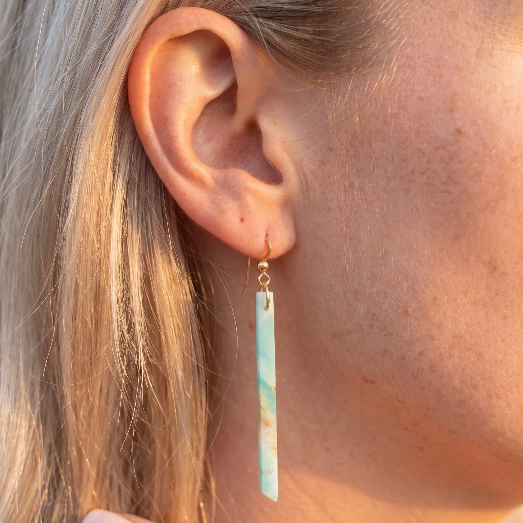 Amazonite long bar earring worn on a model with blonde hair, showing scale and fit with a 14K gold fill fish hook wire, stone in soft blue-green with cream and rust veining