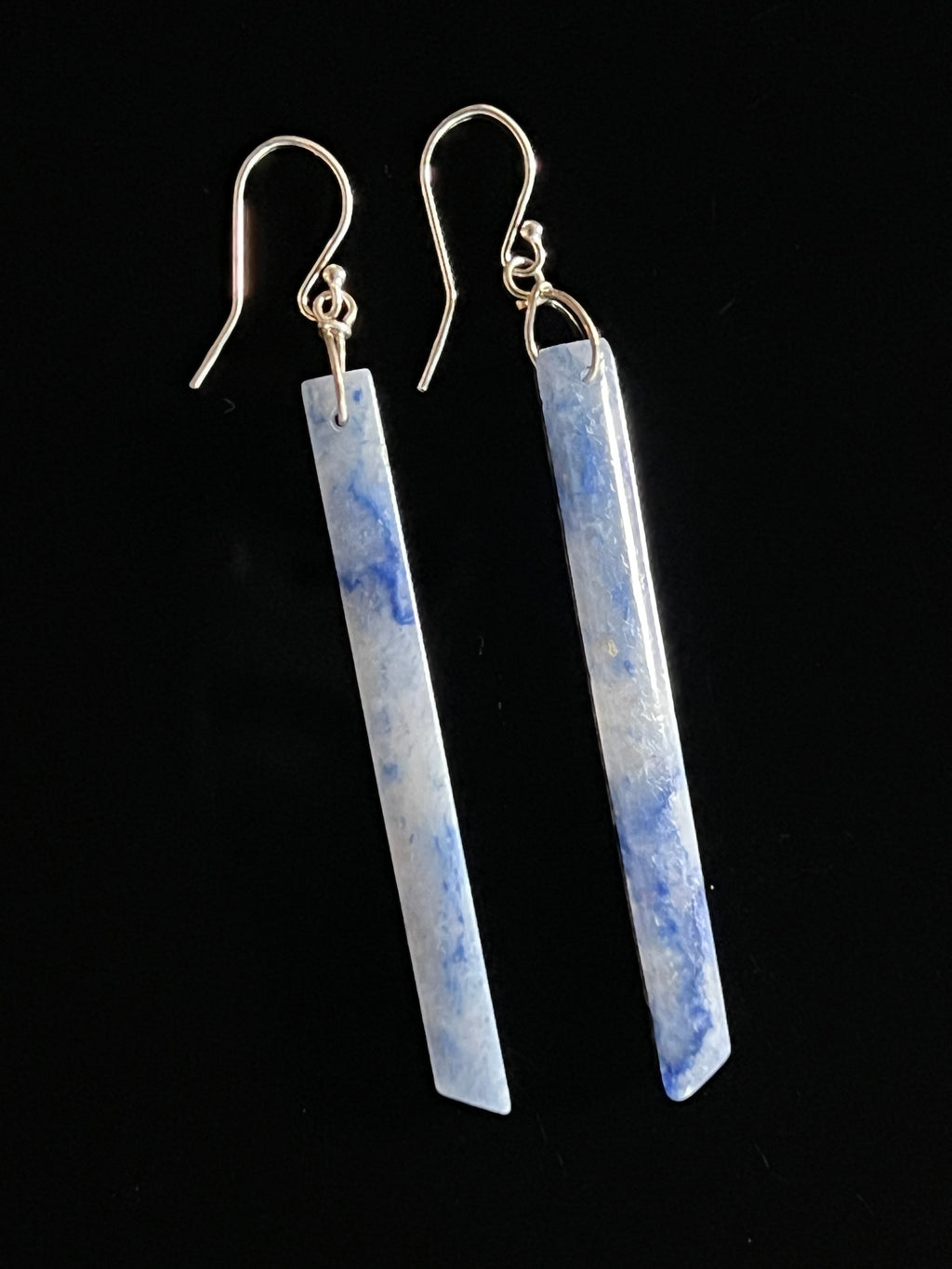 Pair of blue aventurine long bar drop earrings with sterling silver fish hook wires on a black background, showing cerulean and white stone veining