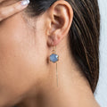 Blue chalcedony flower threader earring in 14K gold fill worn on model, showing faceted periwinkle stone in gold electroform setting with long chain drop