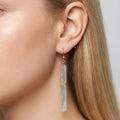 Lemurian calcite long bar earring worn on a model with blonde hair, showing scale and fit with a 14K gold fill fish hook wire against a neutral background