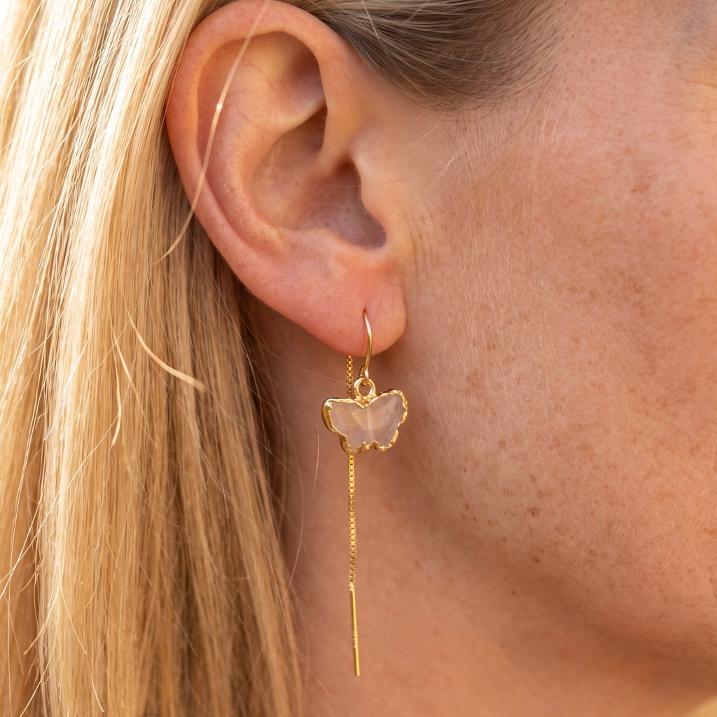 Rose quartz butterfly threader earring in 14K gold fill worn on model, showing carved pale pink stone butterfly with gold electroform frame and long chain drop by Studio MS Indie Jewelry