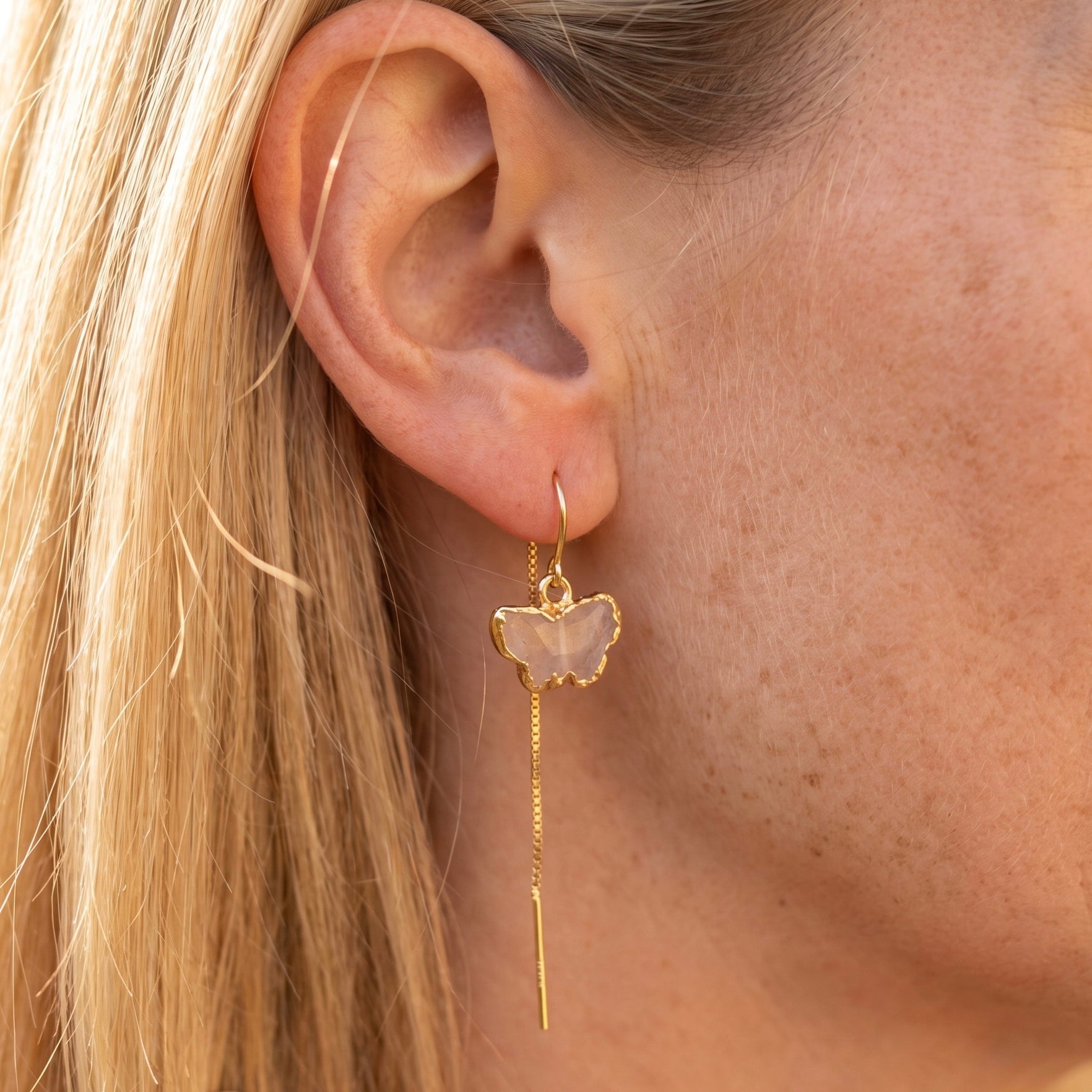 Rose quartz butterfly threader earring in 14K gold fill worn on model, showing carved pale pink stone butterfly with gold electroform frame and long chain drop by Studio MS Indie Jewelry
