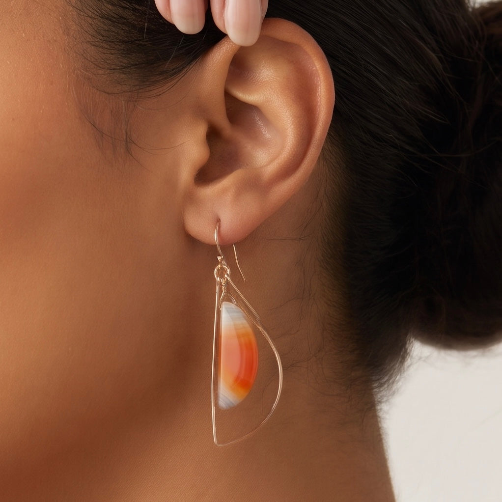 Sardonyx freeform dangle hoop earring in 14K gold fill worn on model, showing banded orange and cream stone inside a hammered gold wire frame