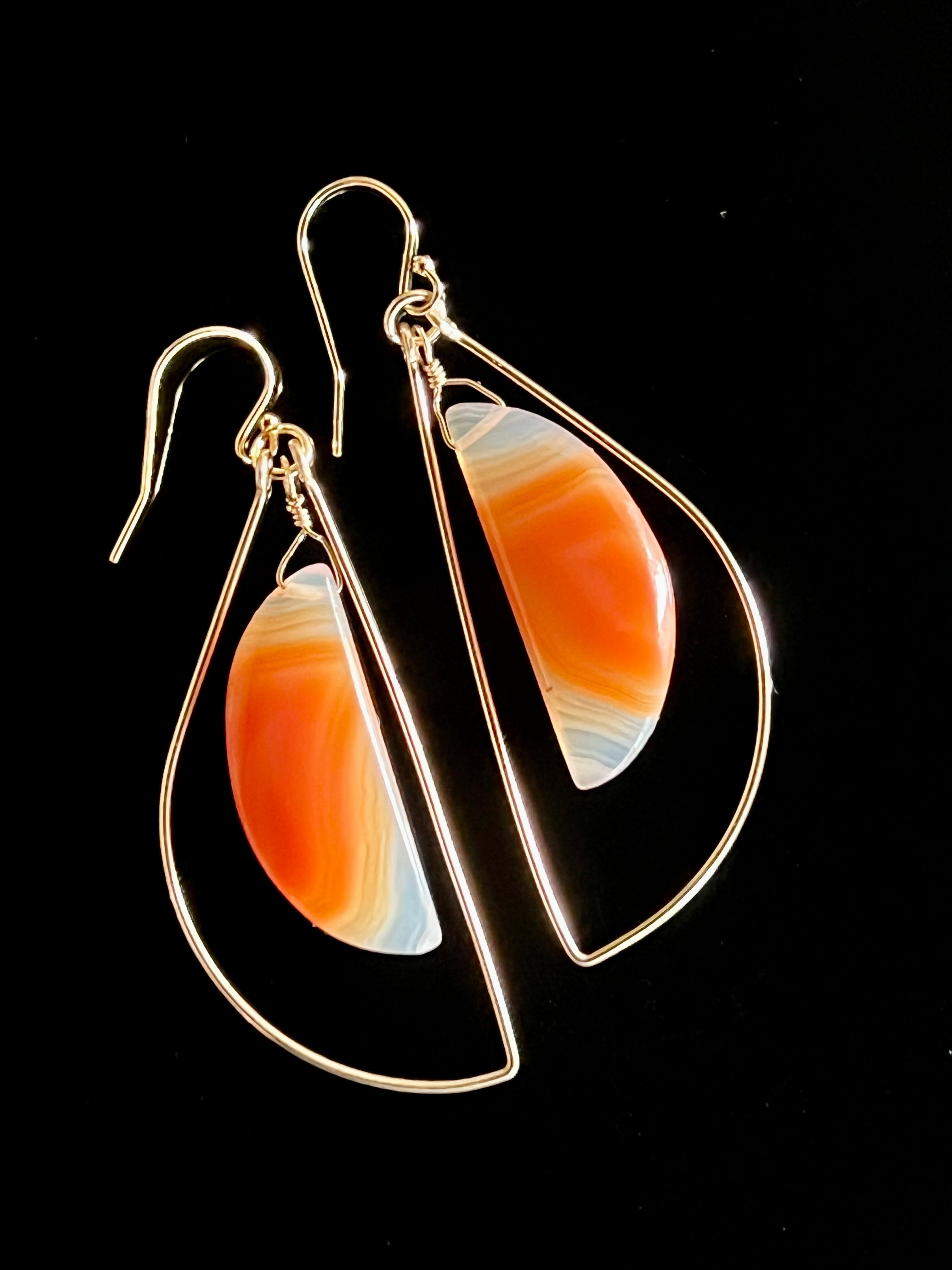 Pair of sardonyx and 14K gold fill freeform hoop earrings on black background, showing banded orange and white stone detail