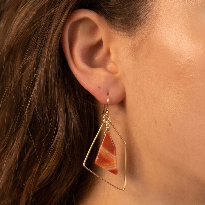 Sardonyx freeform earring in 14K gold fill worn on model, showing banded burnt orange stone inside a hammered geometric gold wire frame